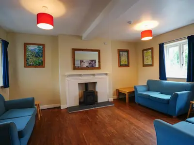 a living room with two blue chairs and a fireplace at YHA Eskdale in Eskdale