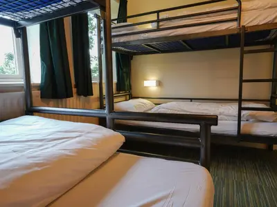 a room with three bunk beds and a window at YHA Eskdale in Eskdale