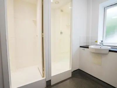 a white bathroom with a shower and a sink at YHA Eskdale in Eskdale
