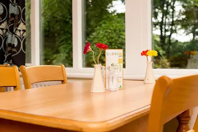 a wooden table with three vases with flowers in them at YHA Grasmere Butharlyp Howe in Grasmere