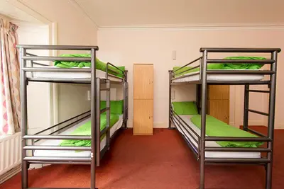 two bunk beds in a room with green sheets at YHA Grasmere Butharlyp Howe in Grasmere