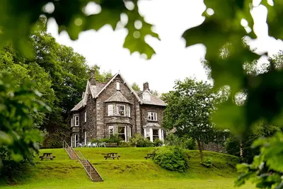 an old stone house on a grassy field at YHA Grasmere Butharlyp Howe in Grasmere