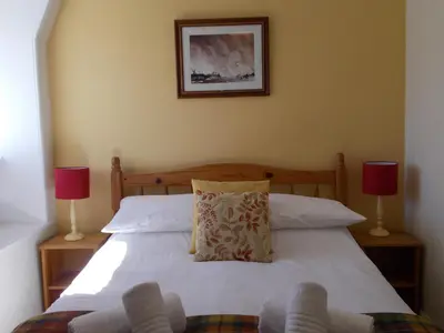 a bedroom with a white bed with two lamps at Swiss Court Guest House in Keswick