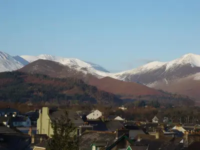 a town with snow covered mountains in the background at Swiss Court Guest House in Keswick