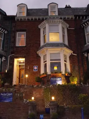 a red brick house with a white window at Swiss Court Guest House in Keswick