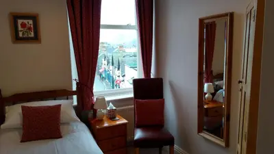 a bedroom with a window and a bed and a chair at Swiss Court Guest House in Keswick