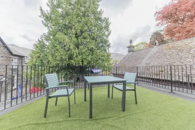a table and chairs on a lawn with a fence at Jacksons CafeBar & Guesthouse in Grasmere