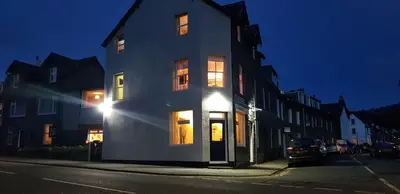 a white house with its lights on on a street at Babbling Brook Guesthouse in Keswick