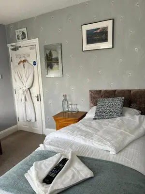 a bedroom with a bed with a remote control on it at Babbling Brook Guesthouse in Keswick