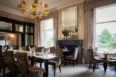 a dining room with tables and chairs and a fireplace at Trout Hotel in Cockermouth