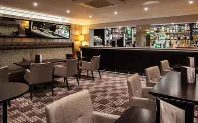a restaurant with tables and chairs and a bar at Trout Hotel in Cockermouth