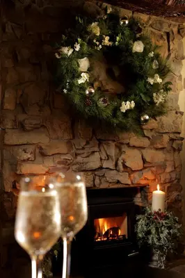 a fireplace with a wreath and two glasses of wine at Trout Hotel in Cockermouth
