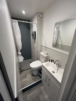 a white bathroom with a toilet and a sink at Dolly Waggon Guest House in Keswick