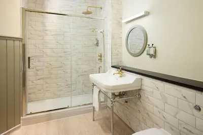 a white bathroom with a sink and a shower at The Pheasant Inn - The Inn Collection Group in Bassenthwaite