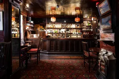 a bar with chairs and a bar counter with alcohol at The Pheasant Inn - The Inn Collection Group in Bassenthwaite