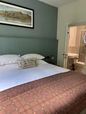 a bedroom with a bed with white sheets and pillows at Royal Oak Hotel in Rosthwaite