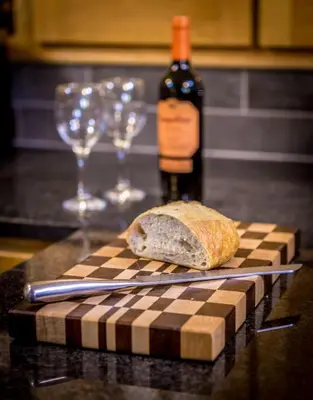a bottle of wine and a loaf of bread and wine glasses at The Garden Apartment in Keswick