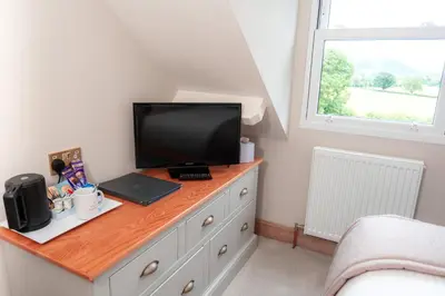a bedroom with a desk with a television on a dresser at The Ruddings in Keswick