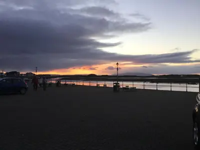 a group of people walking on the beach at sunset at Harbourlights Accomodation in Irvine