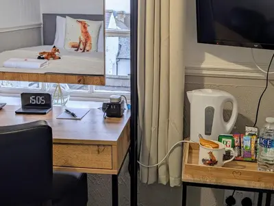 a room with a desk and a table with a television at Graham Arms Inn in Longtown