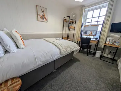 a bedroom with a bed and a desk and a window at Graham Arms Inn in Longtown
