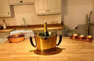 a bottle of champagne in a bucket on a kitchen counter at Bakers Cottage in Cockermouth