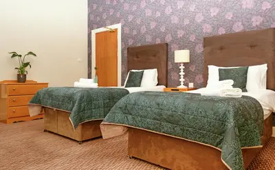a bedroom with two beds with green comforter at The Portpatrick Hotel by Compass Hospitality in Portpatrick