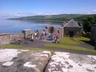 a group of people walking around a castle next to a lake at Woodcroft Cottage in Ayr