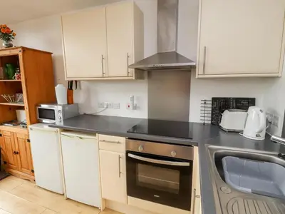 a kitchen with white cabinets and a black counter top at Nuthatch in Ivegill