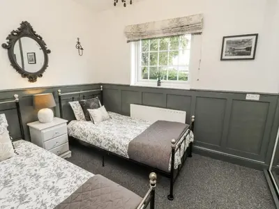 a bedroom with two beds and a mirror and a window at White Gables in Great Clifton