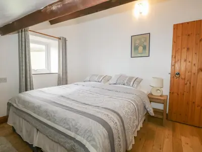 a bedroom with a bed with a white comforter and a window at Bleng Barn Cottage in Seascale