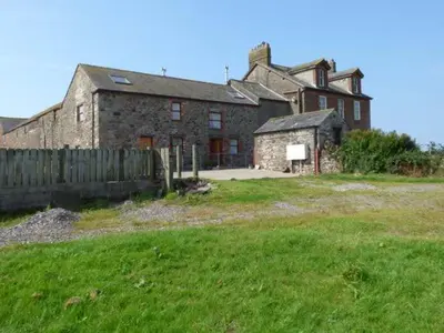 an old brick house with a fence in a field at Muncaster View in Drigg