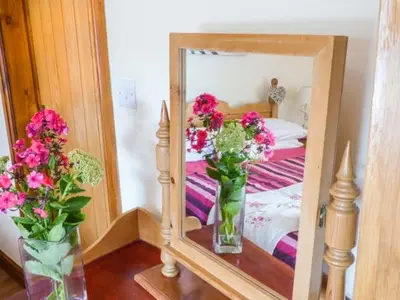 a mirror with two vases of flowers on a table at Muncaster View in Drigg
