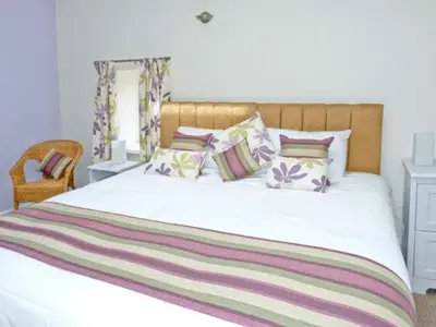 a bedroom with a large white bed with colorful pillows at Chimney Gill in Sebergham
