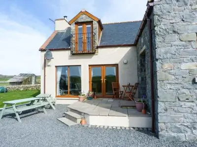 a stone house with a picnic table and a bench at South Milton Cottage in Glenluce