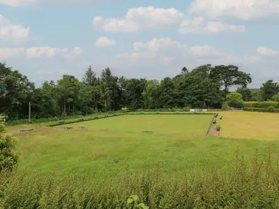 a large grass field with trees in the background at The Old Brewery Store in Gatehouse of Fleet