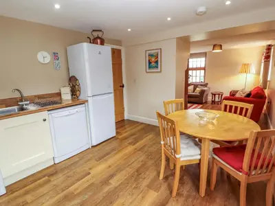 a kitchen and dining room with a table and a refrigerator at The Old Bothy in Wigton