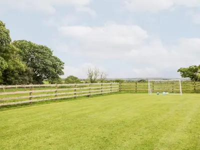 a field with a fence and a soccer goal at The Old Bothy in Wigton