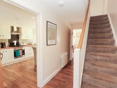 a kitchen and staircase in a home with white cabinets at The Old Grainstore in Wigton