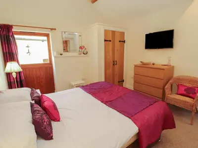 a bedroom with a large bed and a chair at The Old Grainstore in Wigton