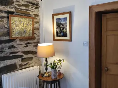 a lamp on a table in a room with a stone wall at High Kiln Bank Cottage in Ulpha
