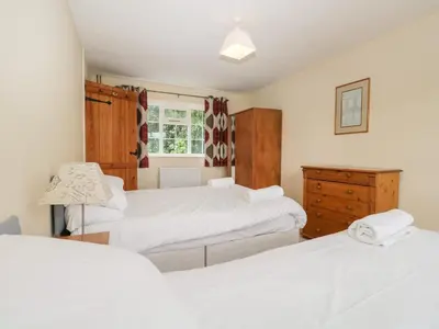 a bedroom with two beds and a dresser and a window at Peel Place Noddle in Eskdale