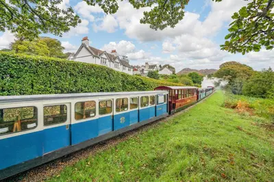 a blue and white train traveling down a hill at Peel Place Noddle in Eskdale