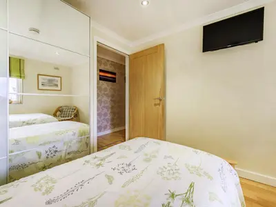 a bedroom with two beds and a television on the wall at Solway Cottage in Bowness-on-Solway