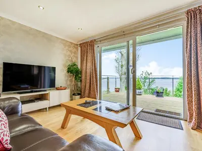 a living room with a table and a large window at Solway Cottage in Bowness-on-Solway