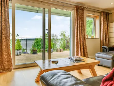 a living room with a table and a large window at Solway Cottage in Bowness-on-Solway