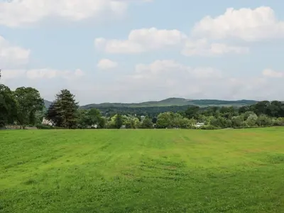 a field of green grass with mountains in the background at 79 Laurel Bank in Gatehouse of Fleet
