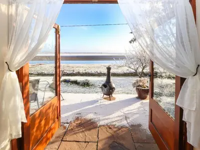 a door to a room with a view of the ocean at Sonya's Cottage in Anthorn