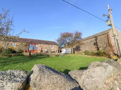 a house with rocks in front of a yard at Sonya's Cottage in Anthorn