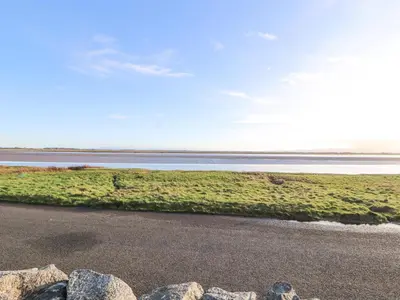a beach with rocks and a body of water at Sonya's Cottage in Anthorn